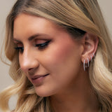 Close-up of a woman wearing hoop earrings with a neutral background